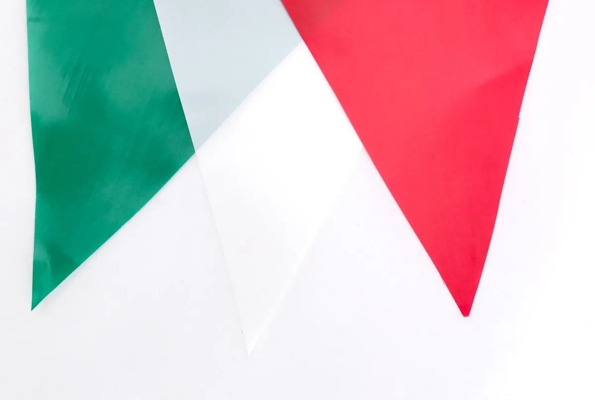 Tira de banderines triangulares intercalados en colores patrios (verde bandera, blanco y rojo) con guía de rafia blanca, ideal para decoración de eventos y fiestas patrias. Material plástico, 50 metros de largo, apto para exteriores.