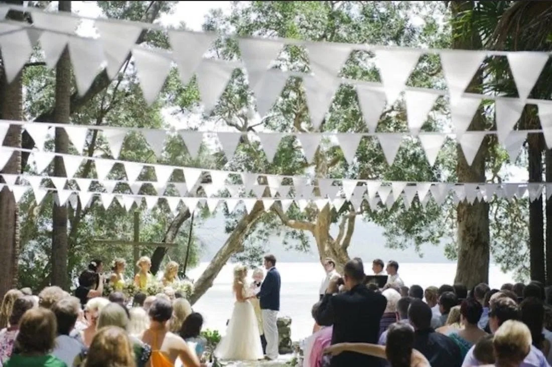 Tira decorativa de banderines triangulares de polietileno color blanco, ideal para eventos al aire libre como bodas, bautizos y ceremonias; 50 metros de largo con 84 banderines por tira.
