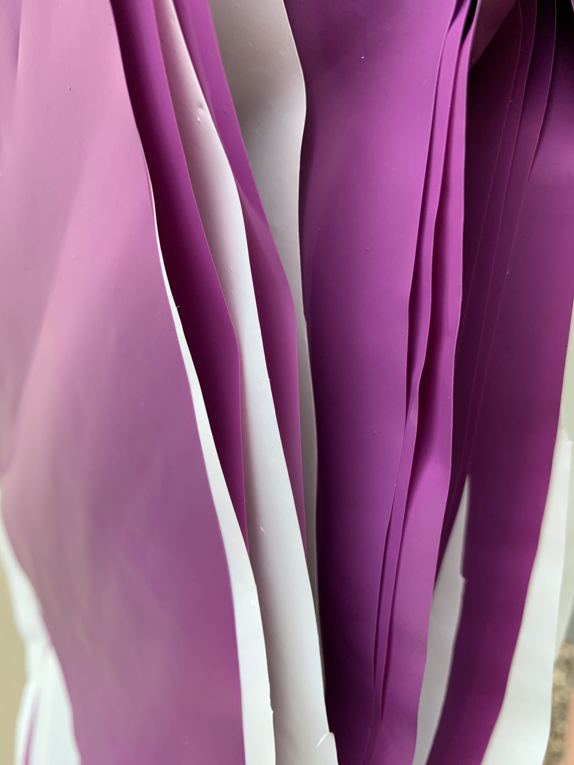 Tira de banderines triangulares colores lila y blanco, fabricados en polietileno resistente con guía de rafia blanca. Perfectos para decoración en eventos, fiestas y celebraciones