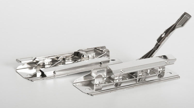 Sujeta documentos de presión metálico con palanca abatible y pisa papeles, incluye remaches para colocación. Diseño de 10 cm de largo, acabado níquel con patrón checkered finish, ideal para organización y sujeción firme de documentos.