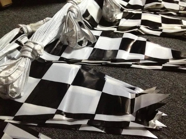 Paquete de 3 tiras de banderines de polietileno con diseño de cuadros negros y blancos estilo carreras, ideales para decoración de fiestas o negocios; 50 metros por tira, 150 metros en total.