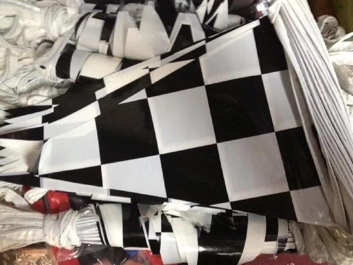 Paquete de 3 tiras de banderines de polietileno con diseño de cuadros negros y blancos estilo carreras, ideales para decoración de fiestas o negocios; 50 metros por tira, 150 metros en total.