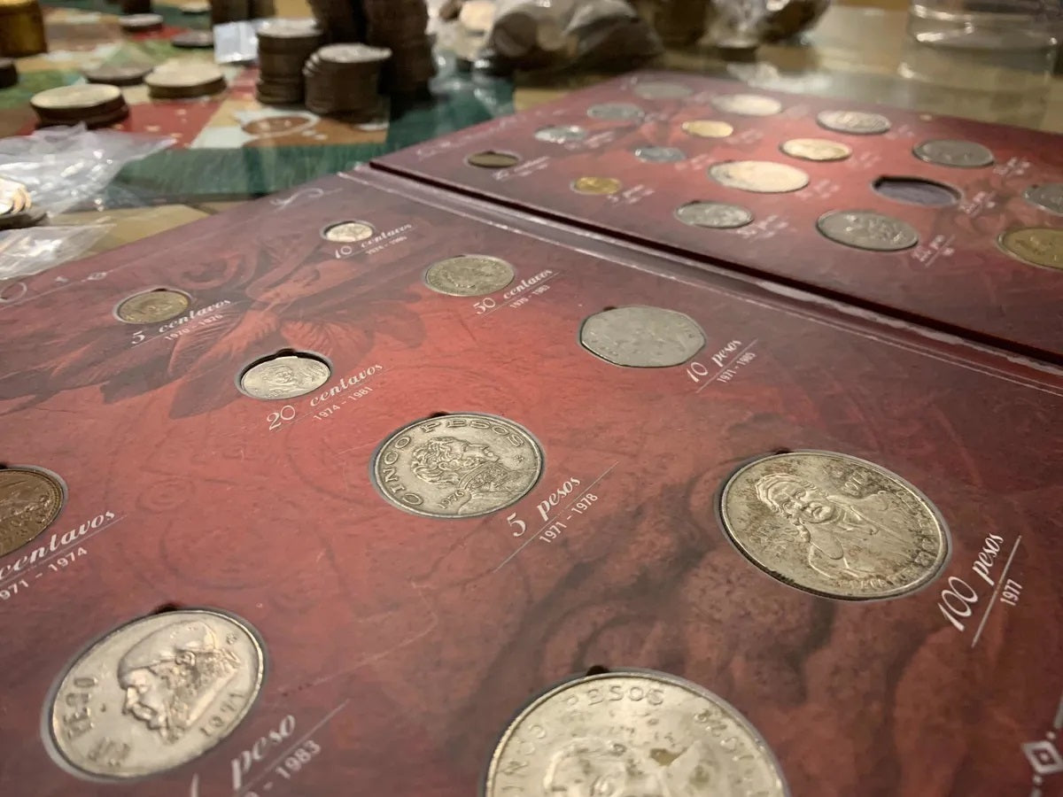 Álbum coleccionador de monedas mexicanas de las décadas de 1970 y 1980, con capacidad para 28 monedas de varias denominaciones, diseño de pasta dura con letras metalizadas doradas y funda protectora.