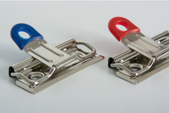 Clip sujetador de documentos a presión con palanca recubierta de plástico en azul rey o rojo, medida de 7 cm de ancho. Ideal para carpetas, tablas, y menús.
